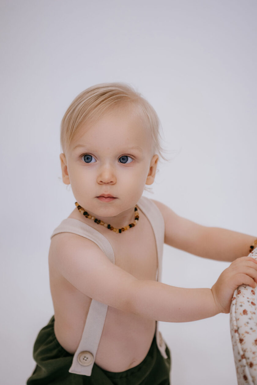 baby wearing multi color unpolished amber necklace