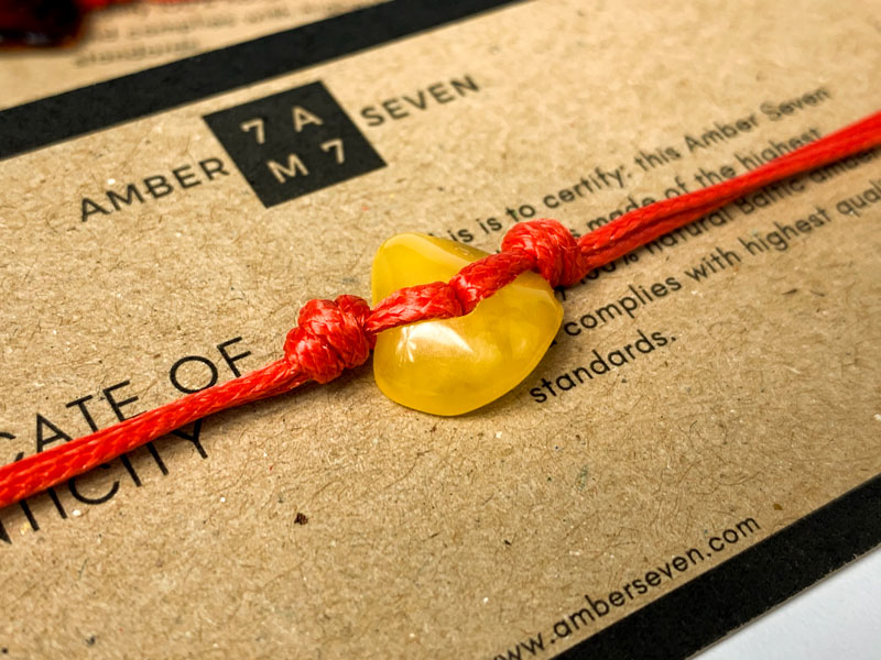 red string friendship bracelet with amber